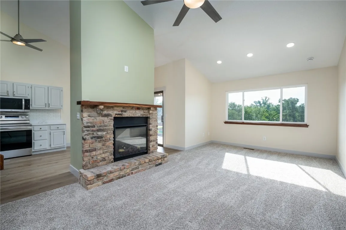 Living area with all new carpet and luxury vinyl flooring, brick fireplace with electric insert