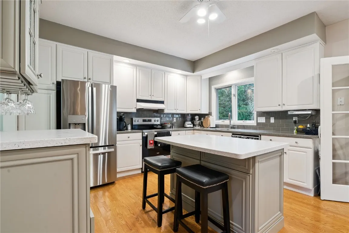 Kitchen with SS appliances and island with stools