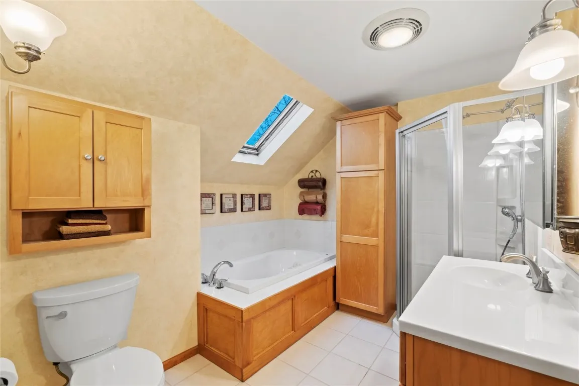 2nd floor bathroom with jetted tub and standing shower stall and skylight