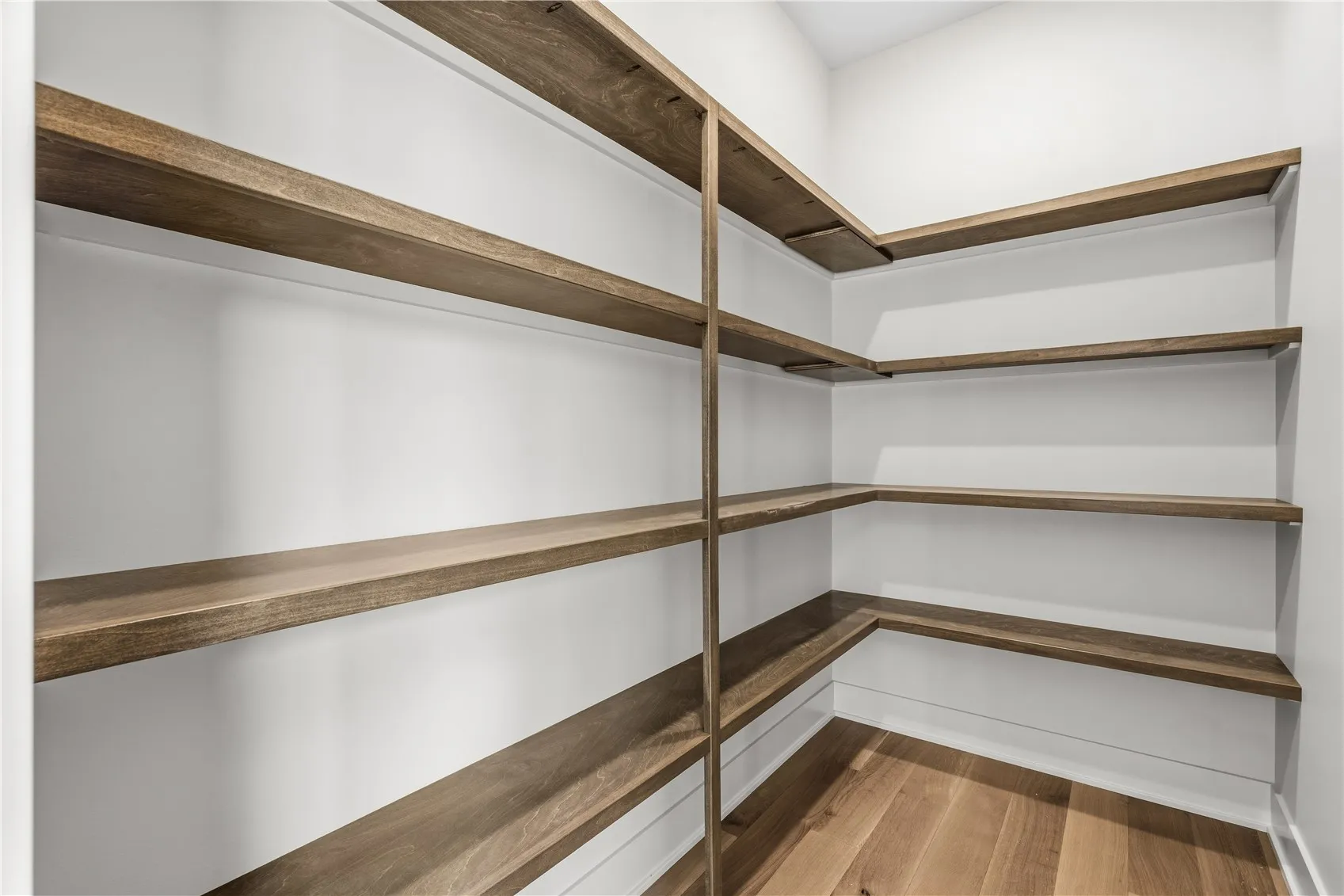 Walk-in pantry with custom wood shelving and pocket door.
