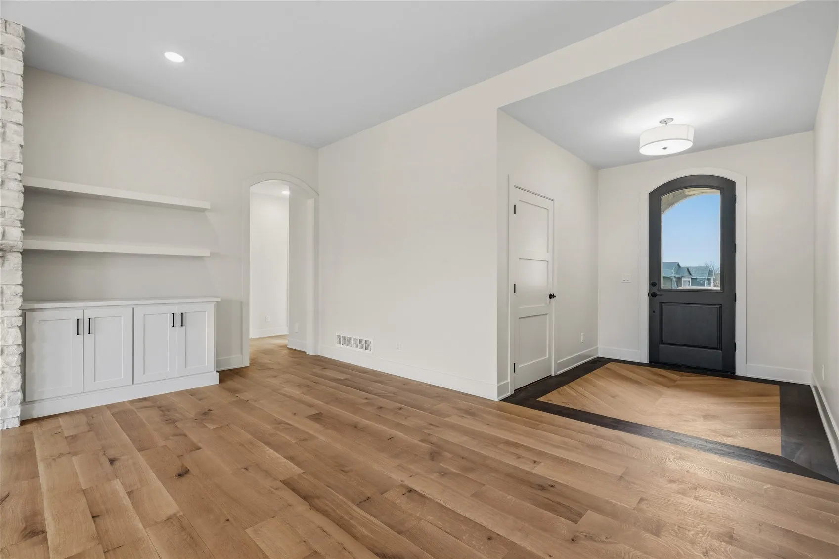Classy archway front door with custom detailed wood floor entry.