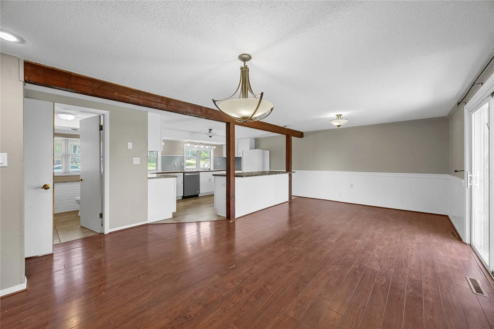 Large dining room area with breakfast island which separates the kitchen from the dining room. On the left is the laundry room and a full bathroom.