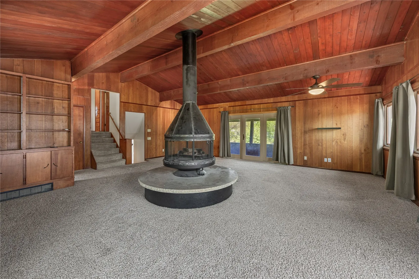 Great room with gas fireplace looking to the northwest. There are a LOT of windows in this room. The ceiling beams are awesome! Note the built in bookshelf.