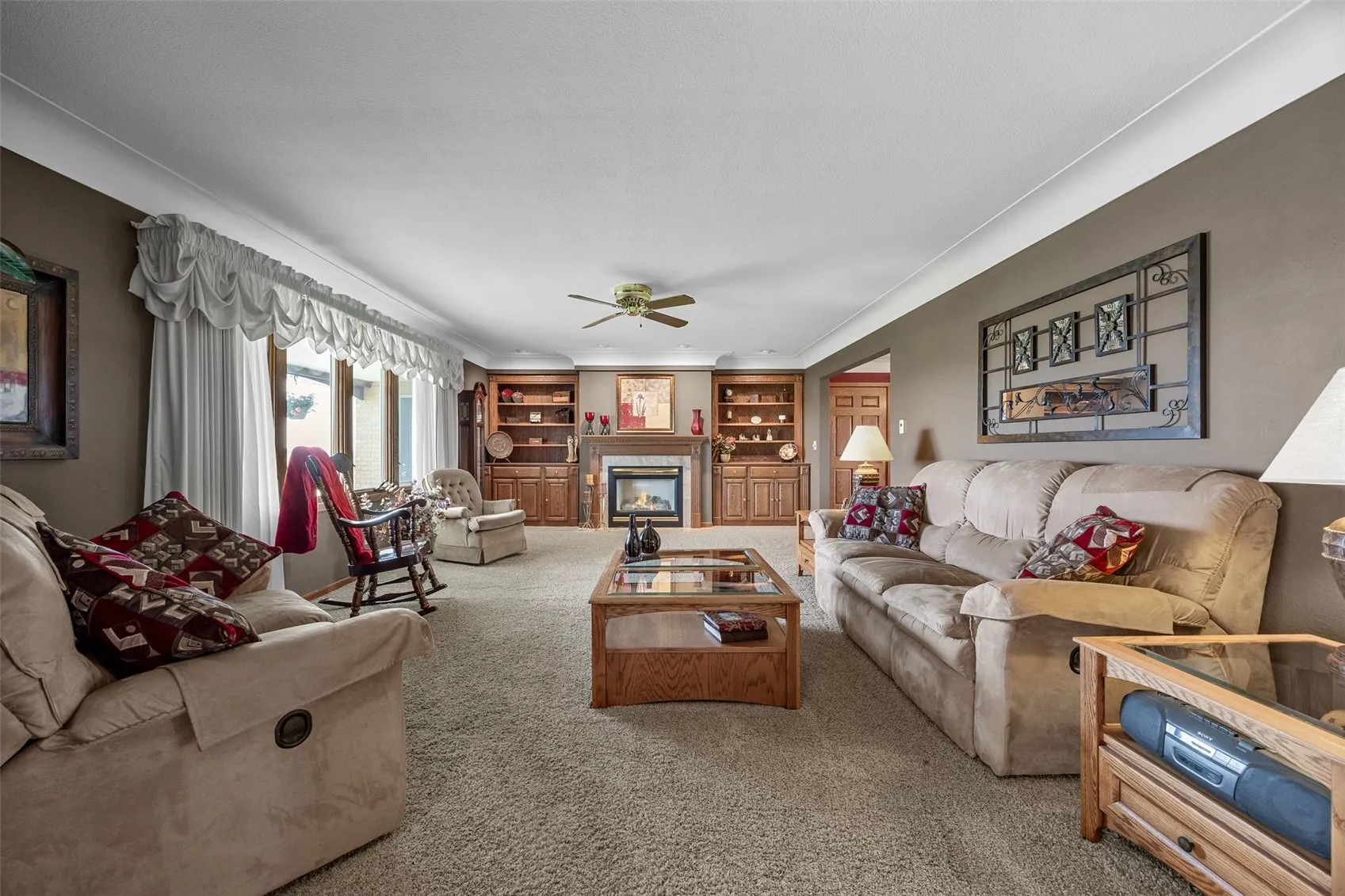 Well maintained living room with gas fireplace and built in shelving.