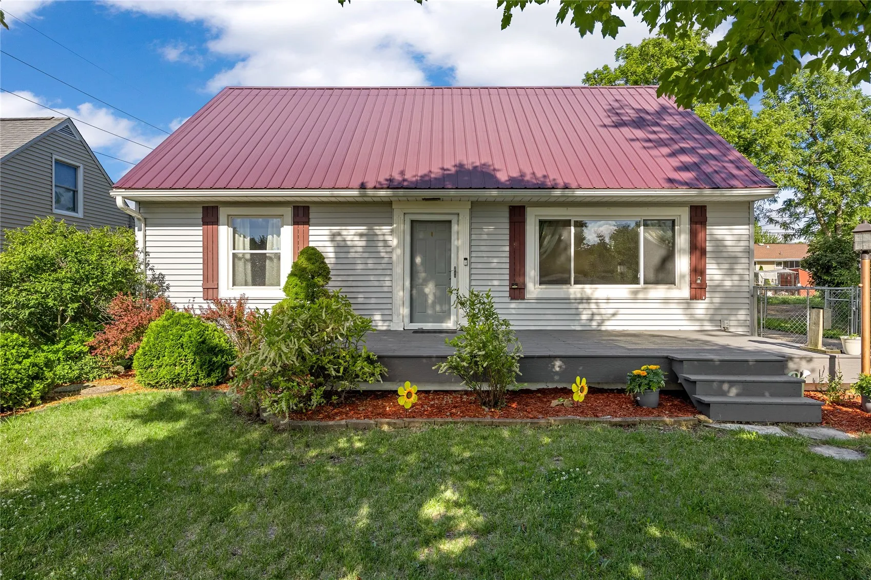 Metal roof, front deck, inviting landscaping