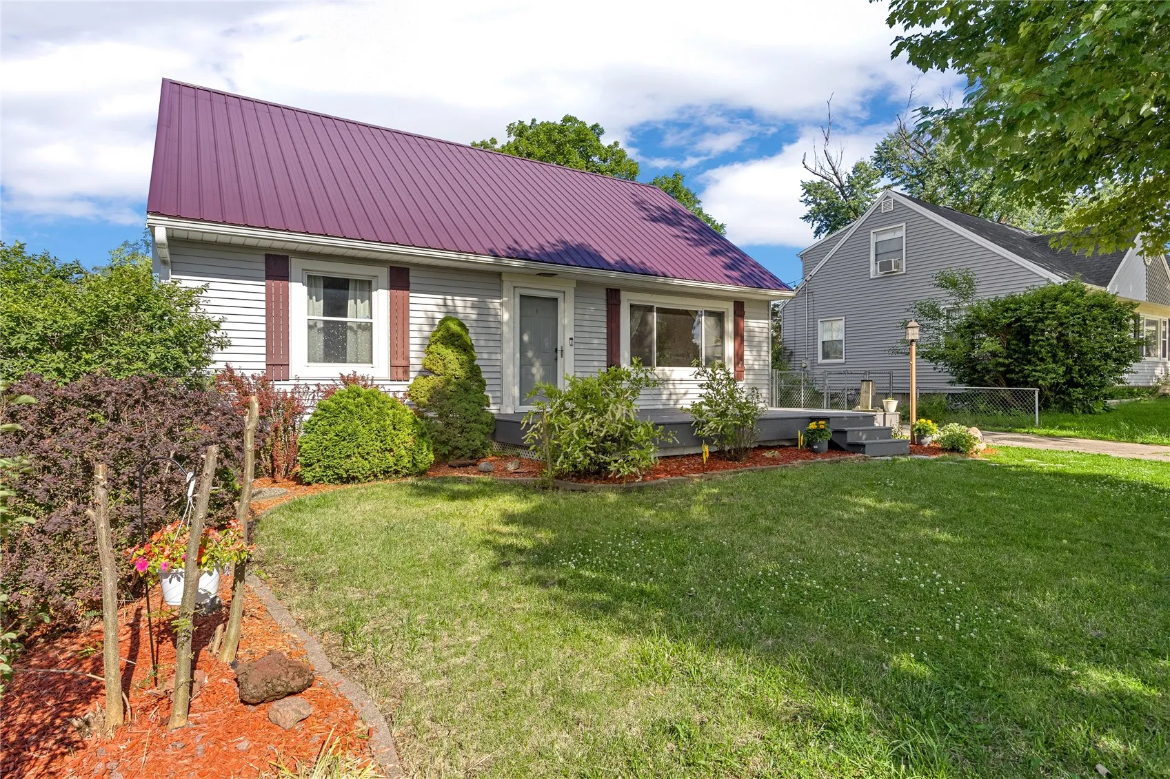 Metal roof, front deck, inviting landscaping