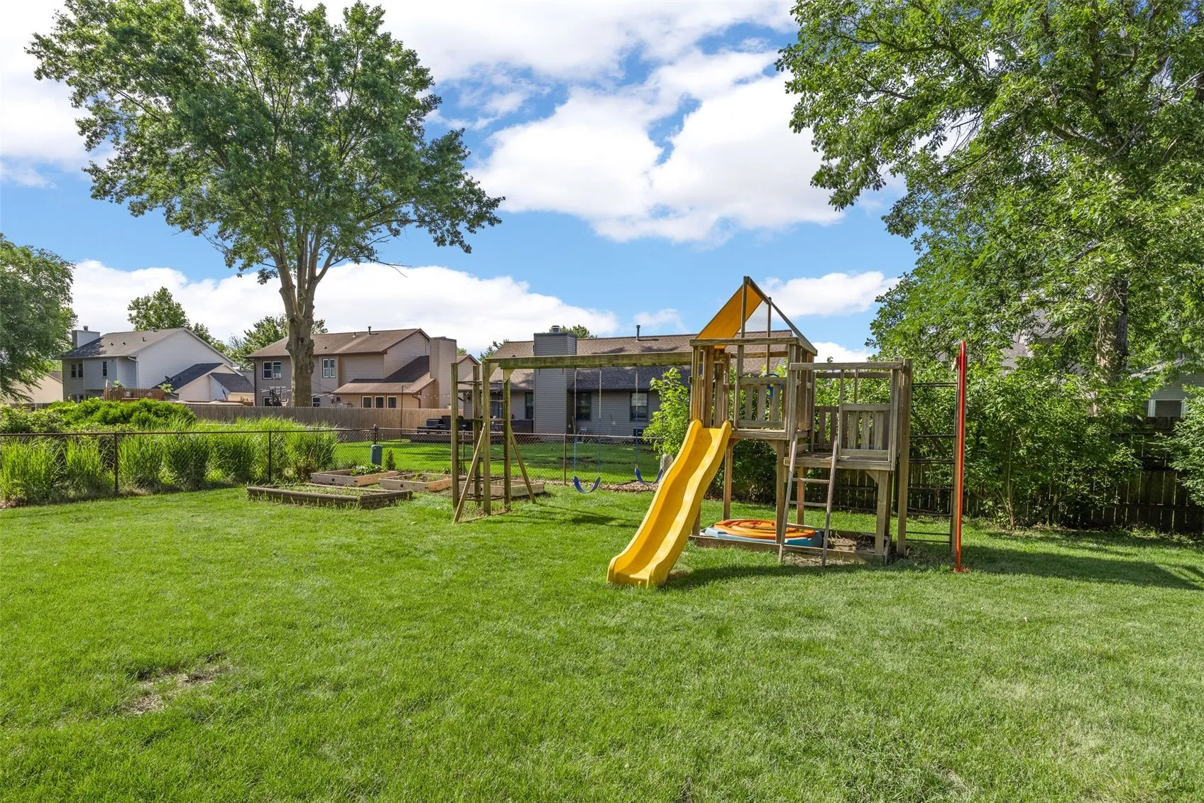 Fenced In Backyard with Swing Set and Garden Plots