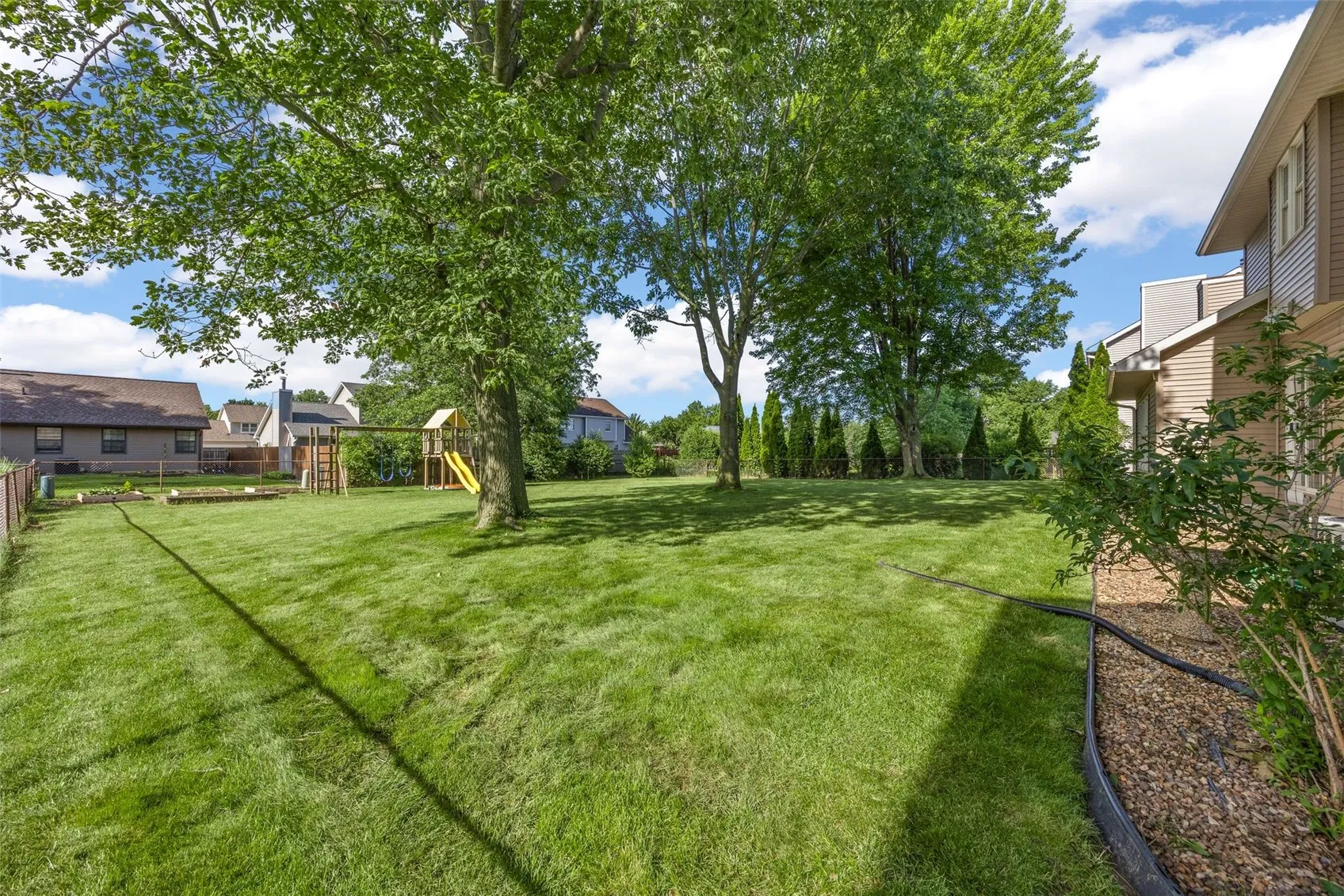 Fenced In Backyard with Swing Set and Garden Plots