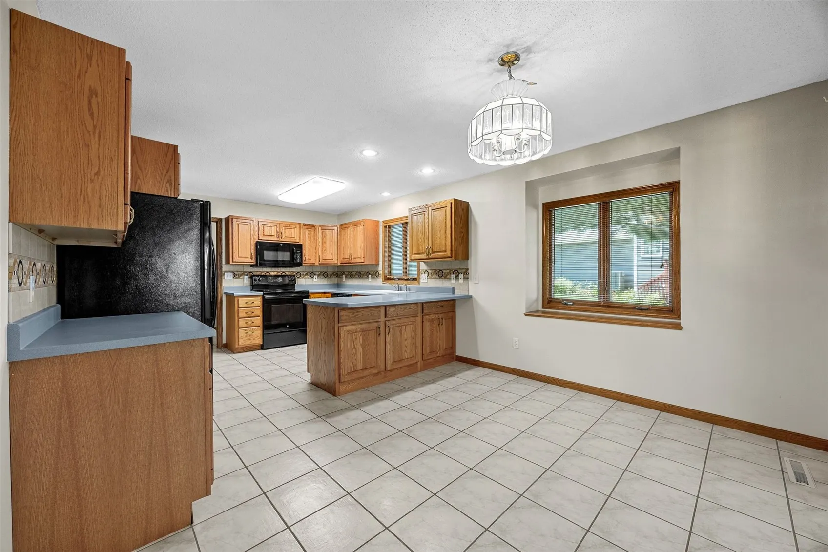 Kitchen features ceramic tile flooring, ample cabinetry, breakfast bar, and open-concept layout flowing into the dining area.