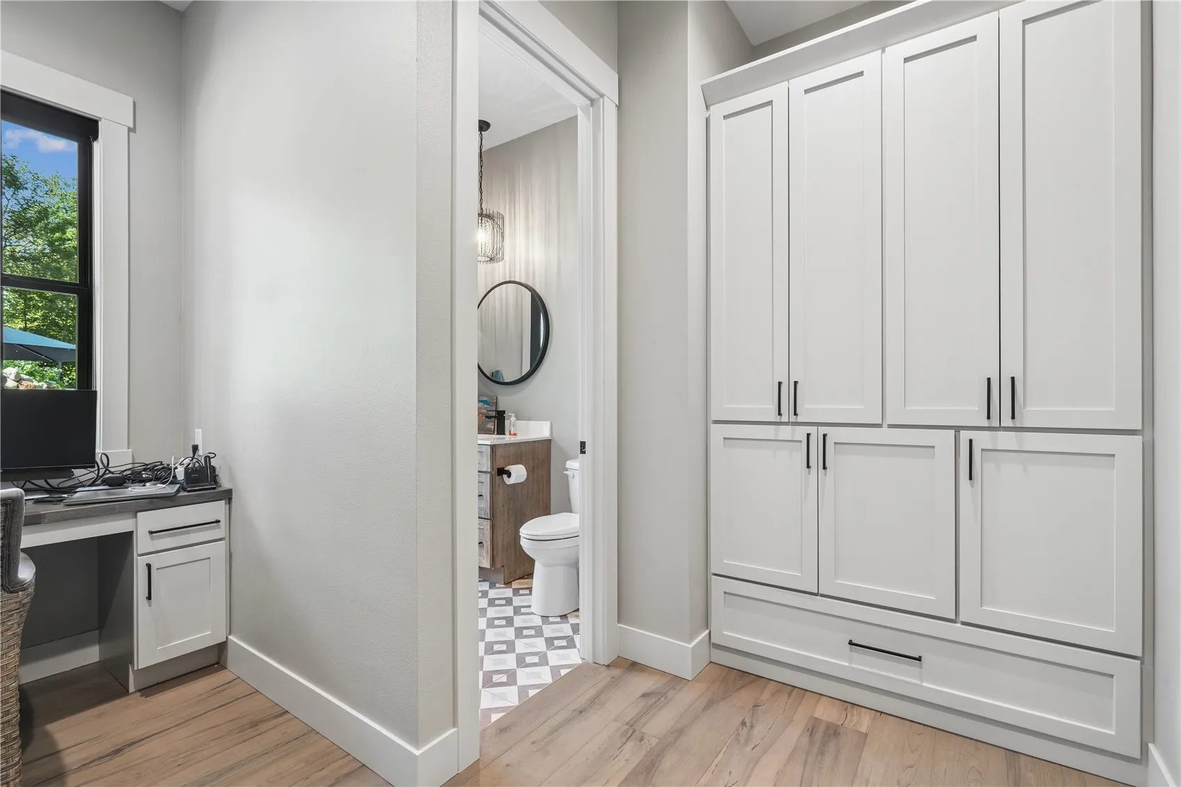 Office with large built-in storage cabinets and access to adjoining half bath.