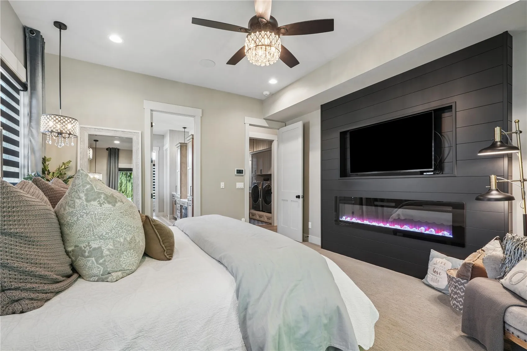 Primary bedroom boasts black shiplap accent wall with electric fireplace.