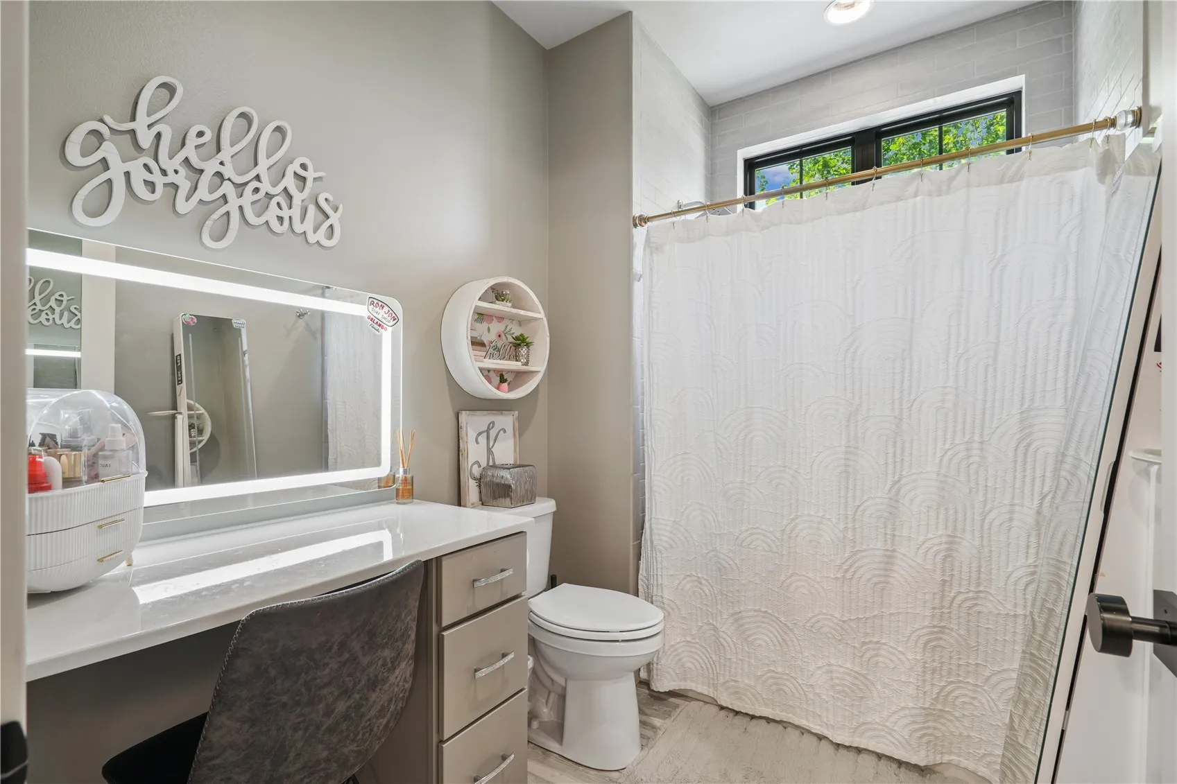 Second half of the Jack and Jill bathroom complete with sitdown vanity with lighted mirror and tile surround for the shower.