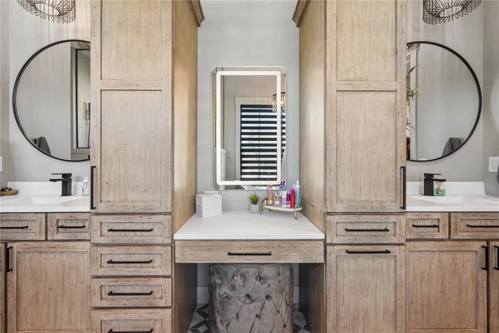 Primary bath with dual vanities and linen cabinets. In addition, there is a sit down vanity with lighted mirror.