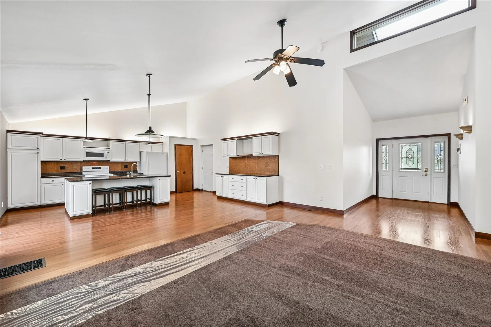 Stunning open floor plan featuring a spacious kitchen island with bar stool seating and an abundance of cabinetry for ample storage.