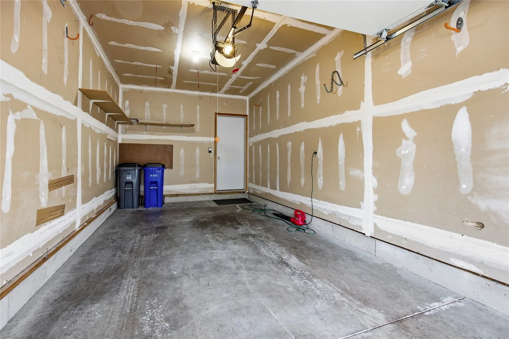 The inside view of the one stall garage. The shelving stays. There is plenty of room for a vehicle and you don't need a lawn mower or a snow blower! There is one space on the newly paved asphalt for an additional vehicle. You enter a hallway through the door at the front of the garage to get to UNIT B.