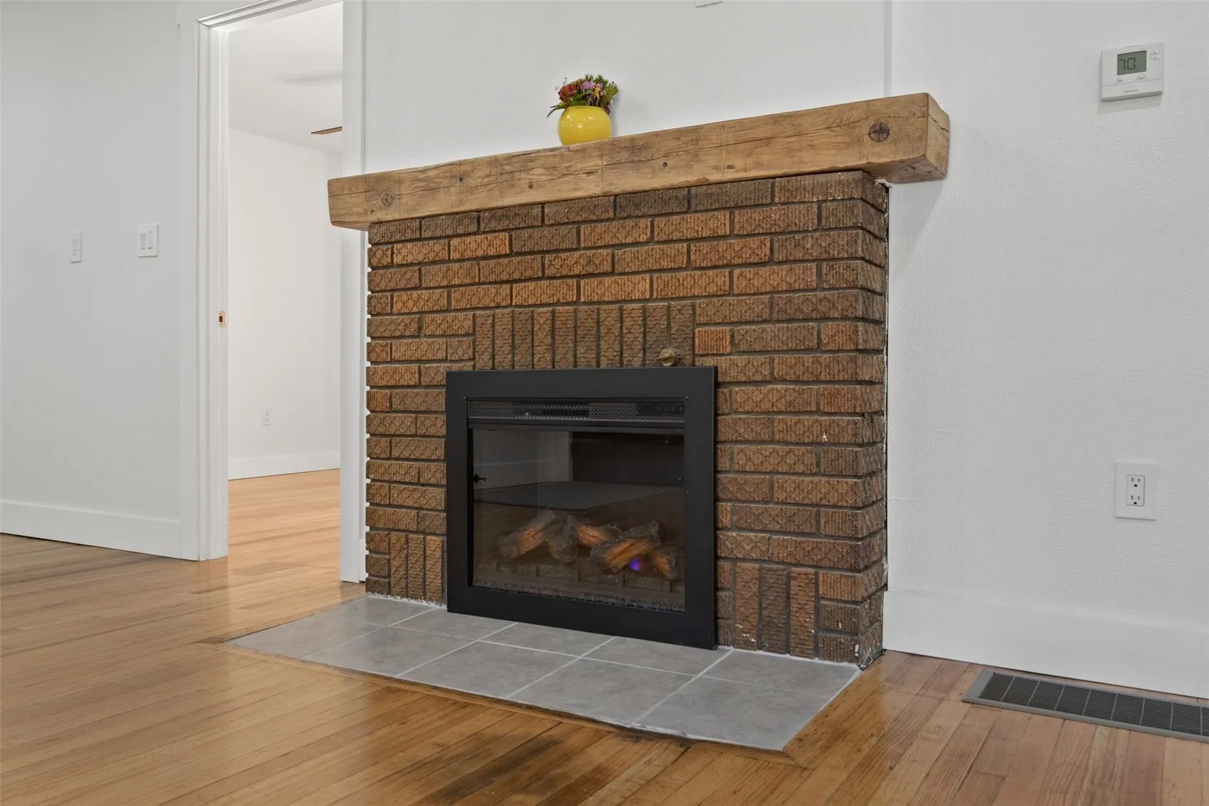 Fireplace featuring original brick with modern electric insert and stunning mantle