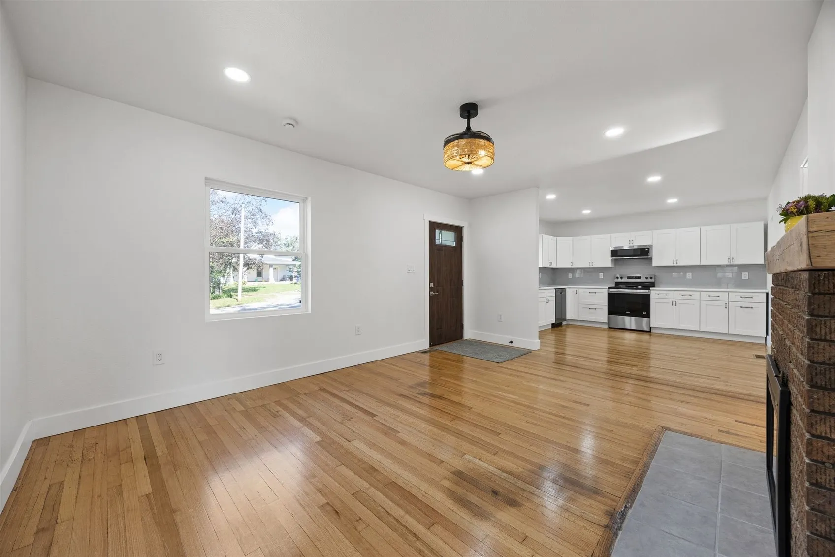 View of living room into kitchen with front door towards center of image