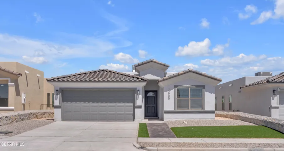 Stucco exterior with a tile roof, an integrated two-car garage, a concrete driveway, a paved walkway, and artificial turf