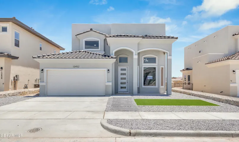 Stucco exterior with arched entryways, concrete driveway, and shingle roof