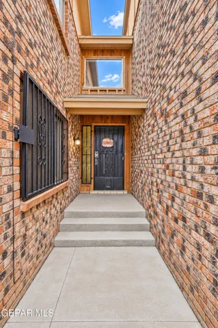 Brick exterior with window security bars, a covered entry, and a multi-pane glass door with a sidelight