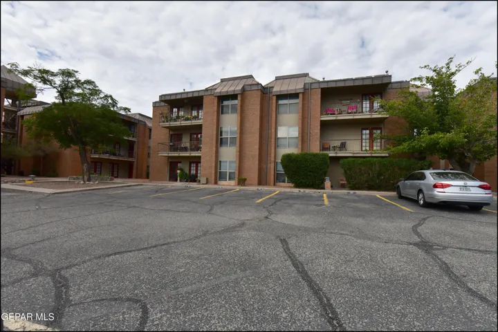 Brick exterior with multiple balconies and a paved parking area