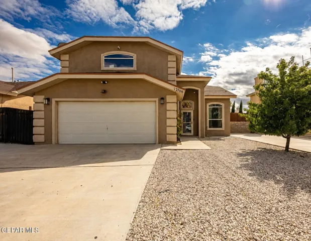 Stucco exterior featuring an attached two-car garage, arched window, and gravel landscaping