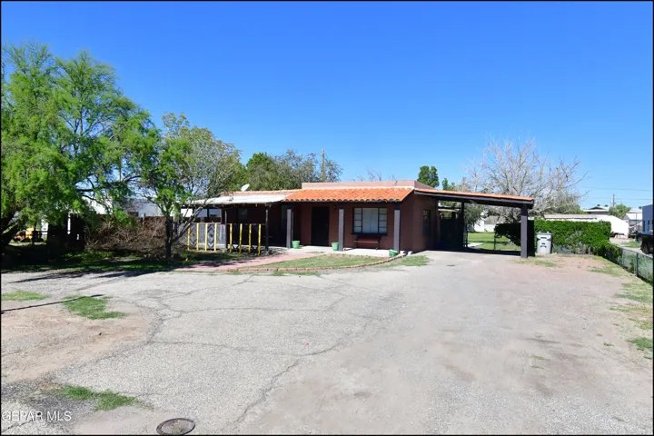 Brown stucco exterior with a terracotta tile roof, covered front porch, and an attached carport