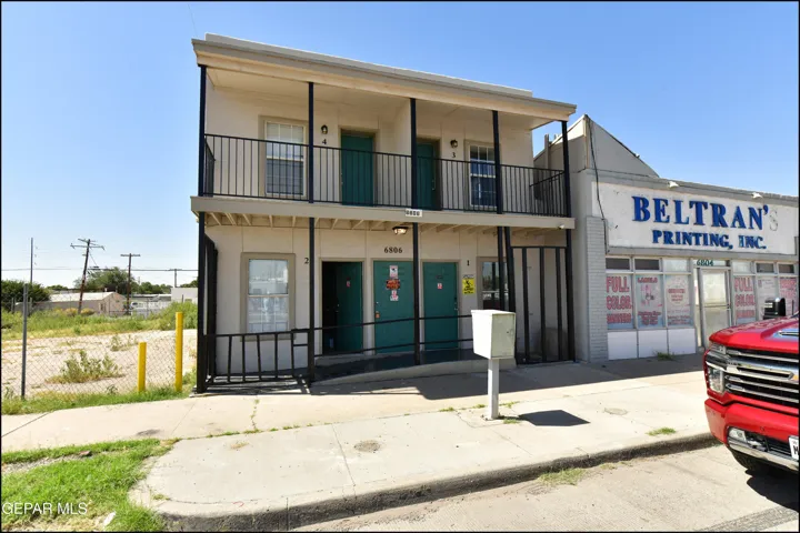 Two-story exterior featuring a second-level balcony with metal railings and an exterior ramp