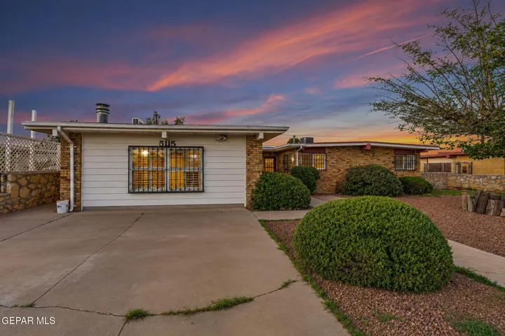 Single-story residence featuring a combination brick and horizontal siding facade, low-pitch roofline, concrete driveway, and ornamental metal window security bars