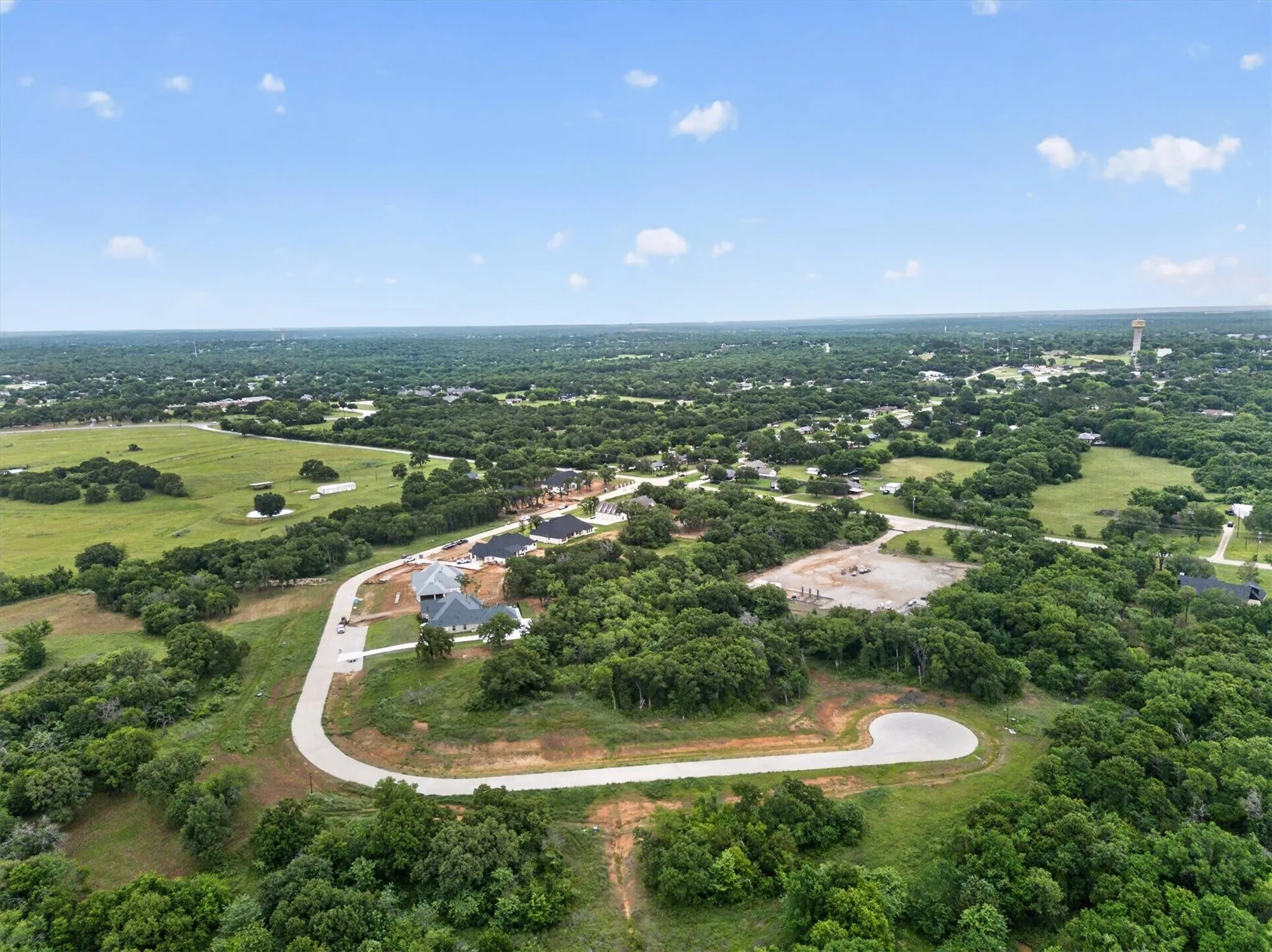 Expansive undeveloped land featuring a cul-de-sac, new construction homes, and surrounding green spaces