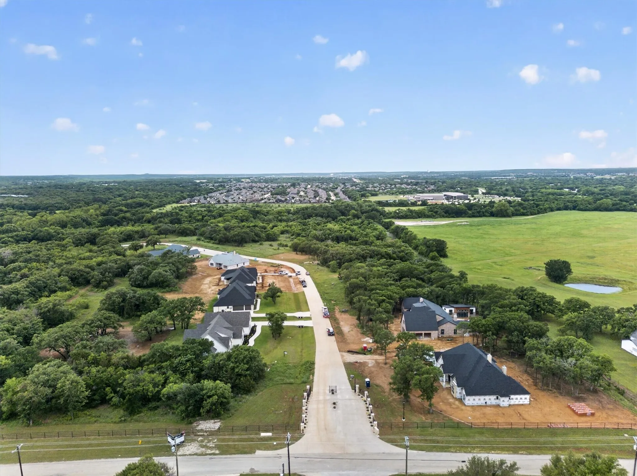 Newly constructed residences within a developing community, featuring a paved street and mature surrounding trees