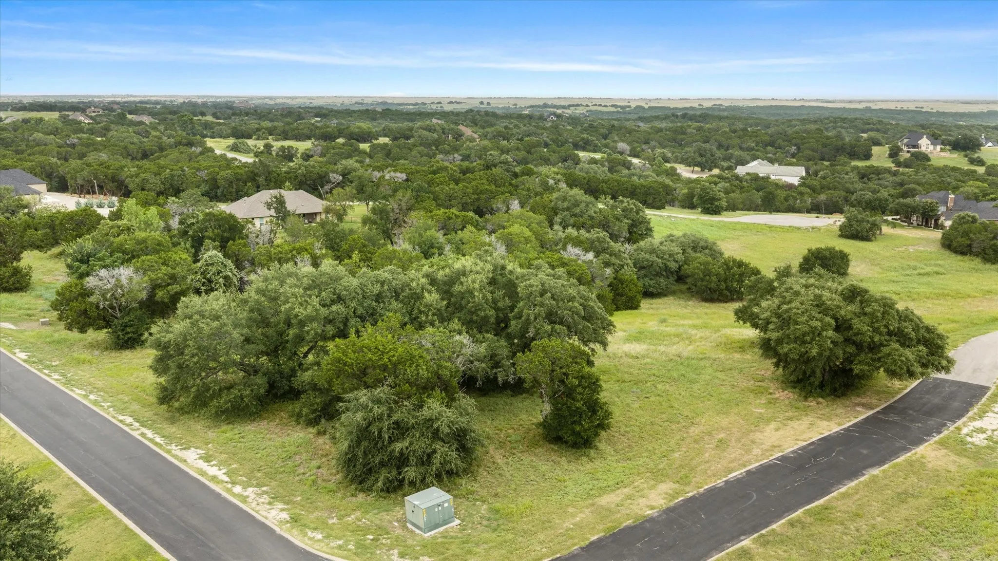 Expansive lot featuring mature trees and a gently sloping terrain, bordered by paved roads