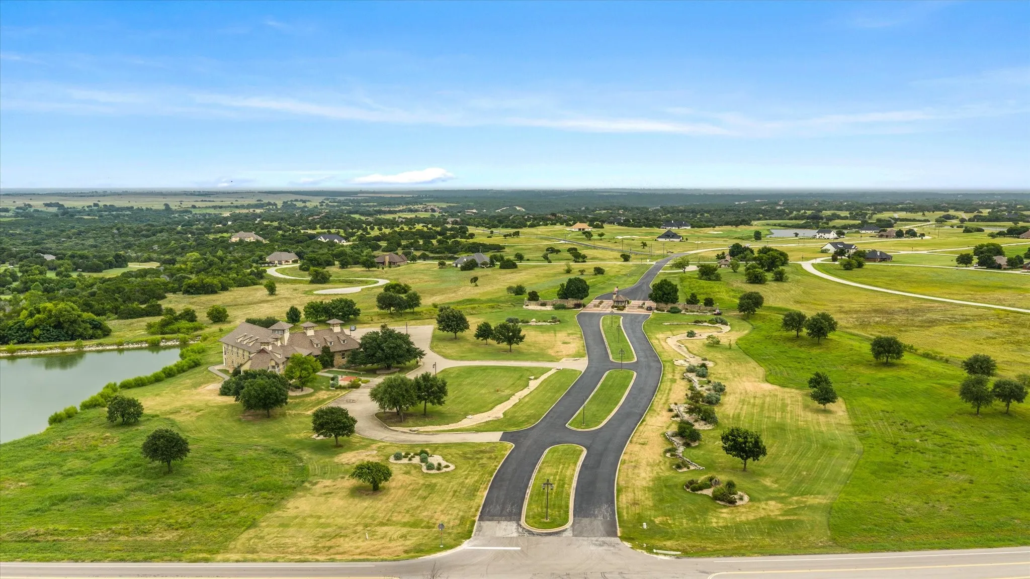 Expansive landscape featuring an asphalt road system, a large body of water, and scattered trees