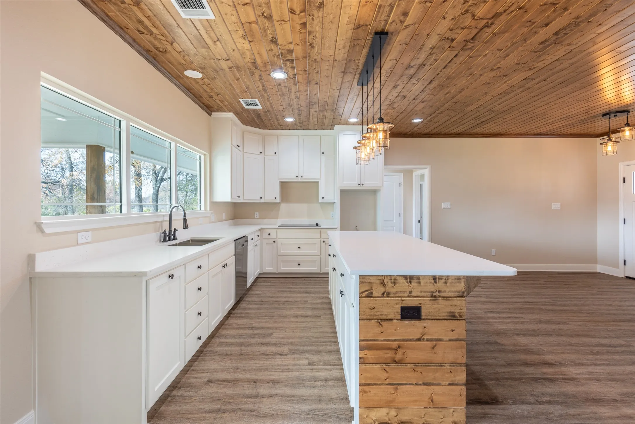 Example Photos: Kitchen featuring a wood-panel accent ceiling, white cabinetry, a large island with wood-finish siding, white countertops, and wood-finish flooring