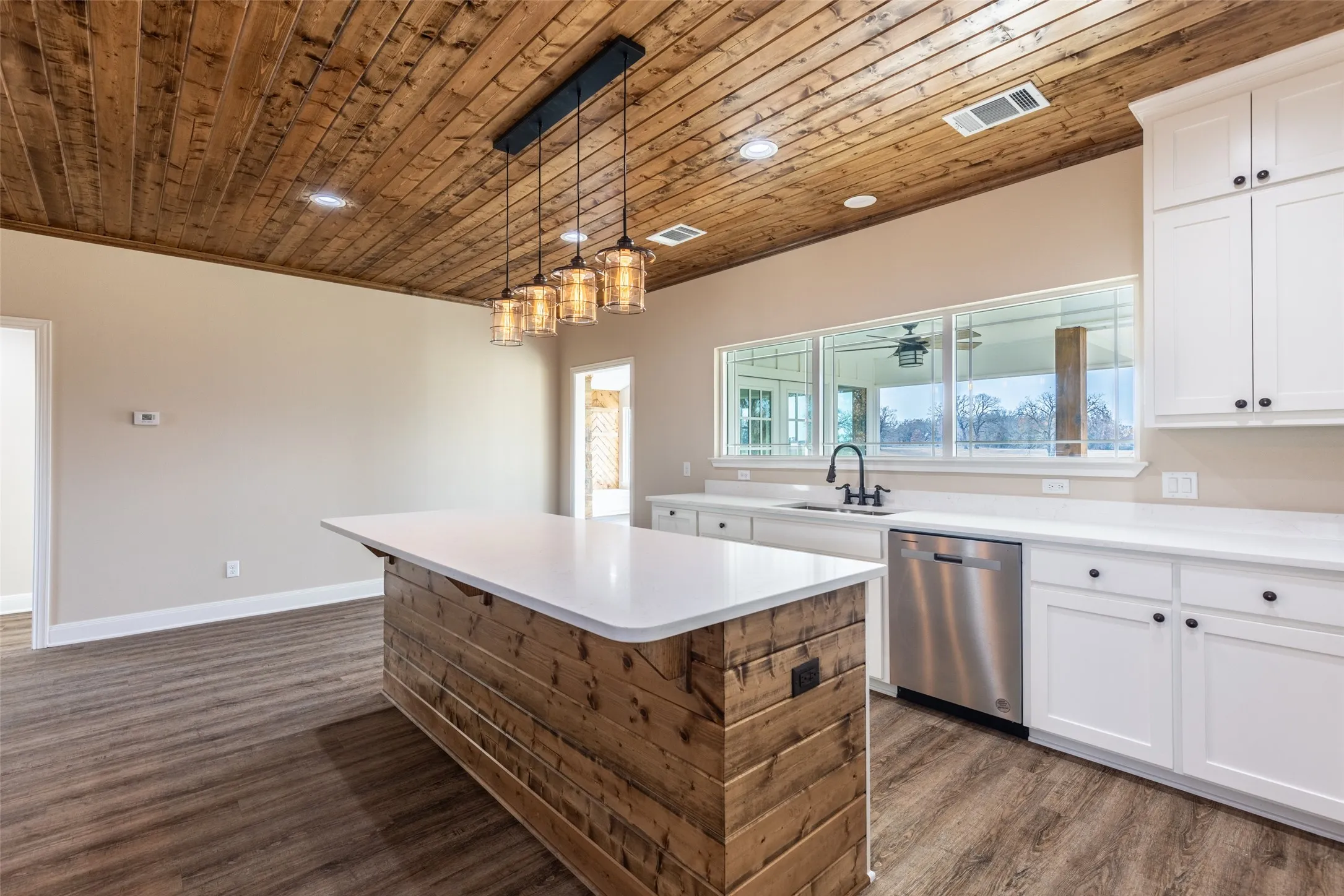 Example Photos: Kitchen featuring a wood plank ceiling, a wood-wrapped island with a white countertop, and pendant lighting
