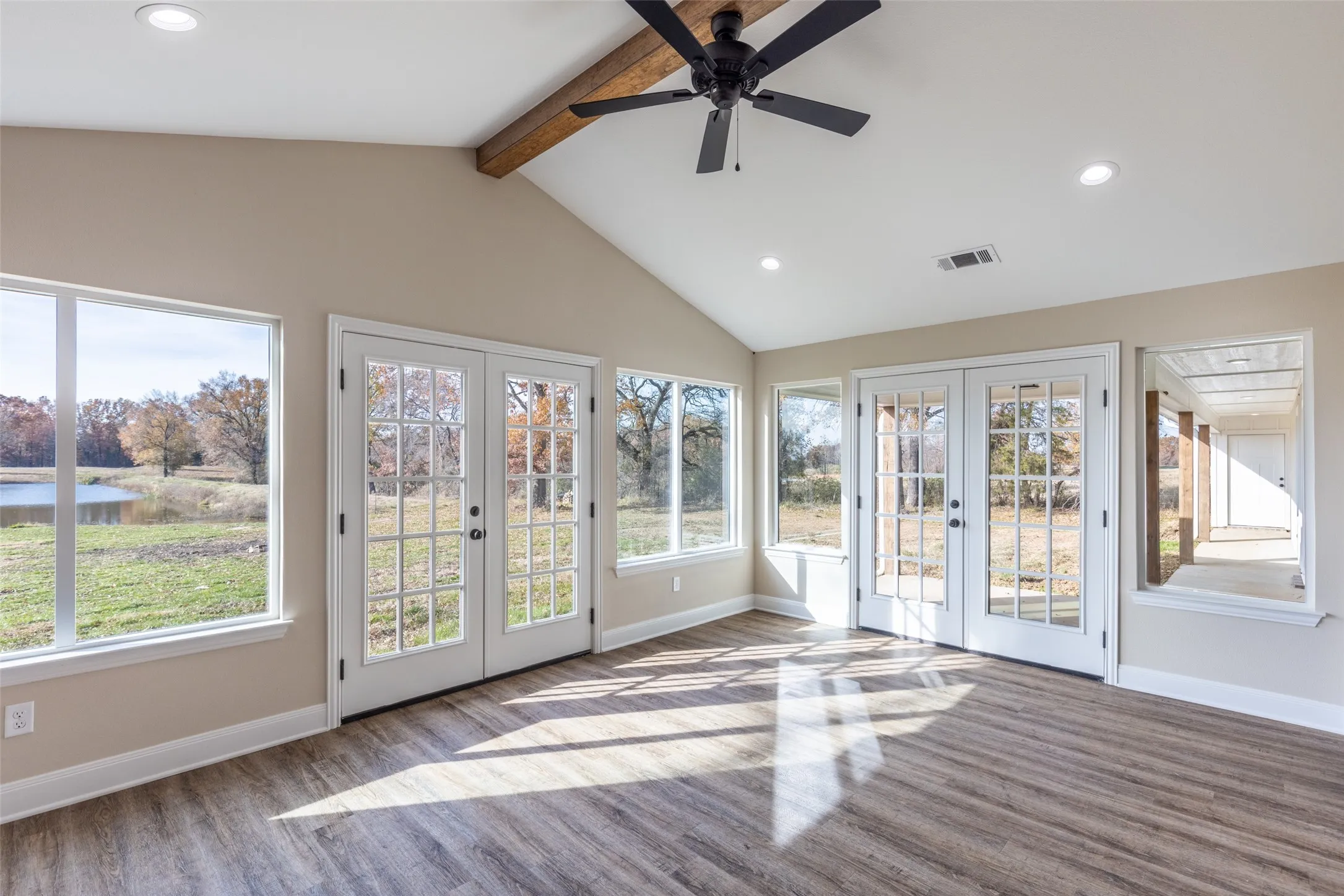 Example Photos: Vaulted ceiling sunroom with wood-finish flooring, recessed lighting, and a visible wood beam