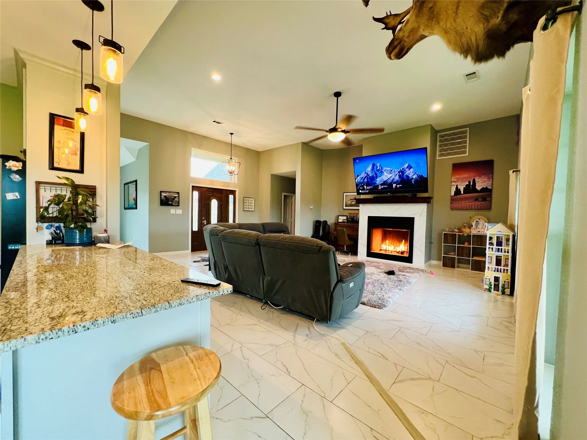 Living room with light tile flooring, ceiling fan, and a fireplace