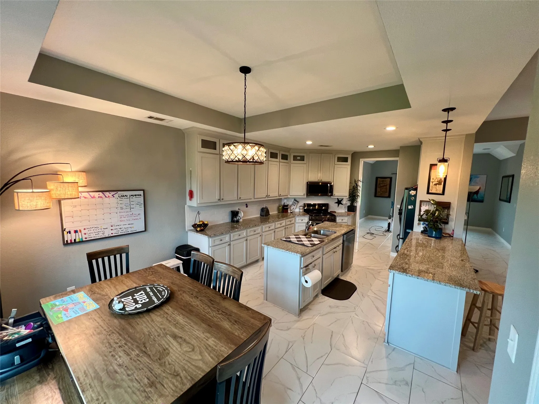 Dining room with an inviting chandelier, sink, a tray ceiling, and light tile flooring