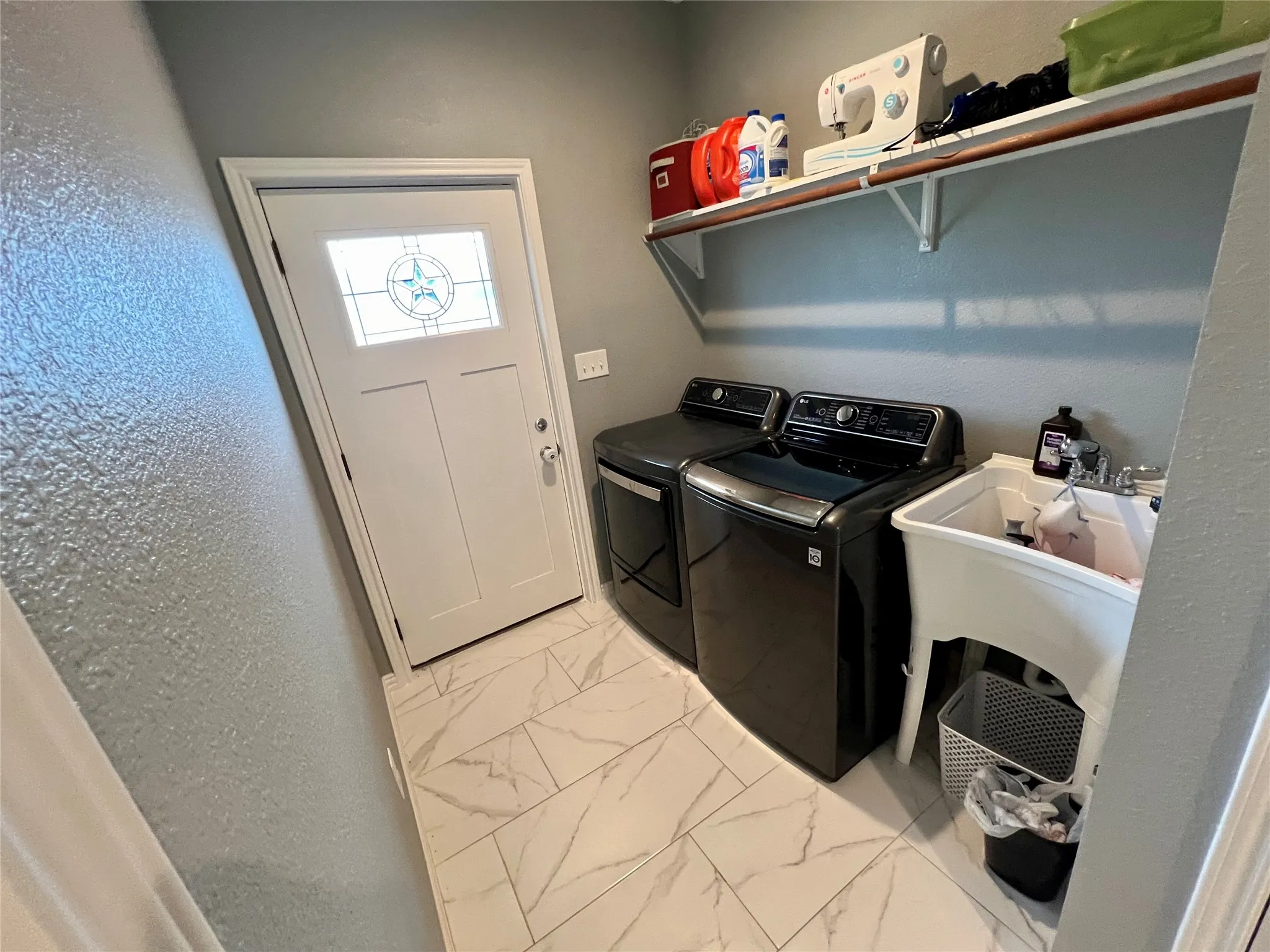 Clothes washing area featuring washer and dryer and light tile flooring