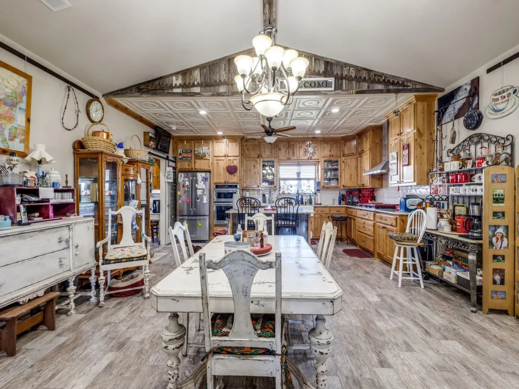 Dining space featuring vaulted ceiling, light hardwood / wood-style flooring, and ceiling fan with notable chandelier
