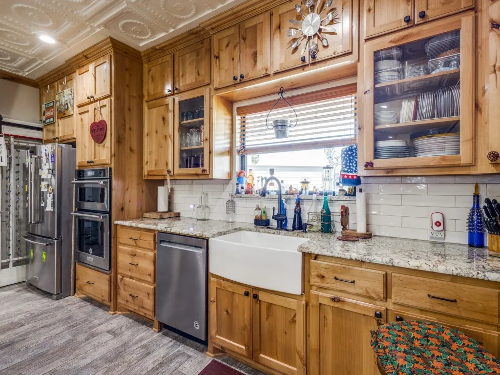 Kitchen with light stone countertops, appliances with stainless steel finishes, backsplash, sink, and light wood-type flooring