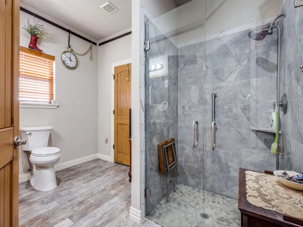 Bathroom with hardwood / wood-style floors, toilet, and a shower with shower door