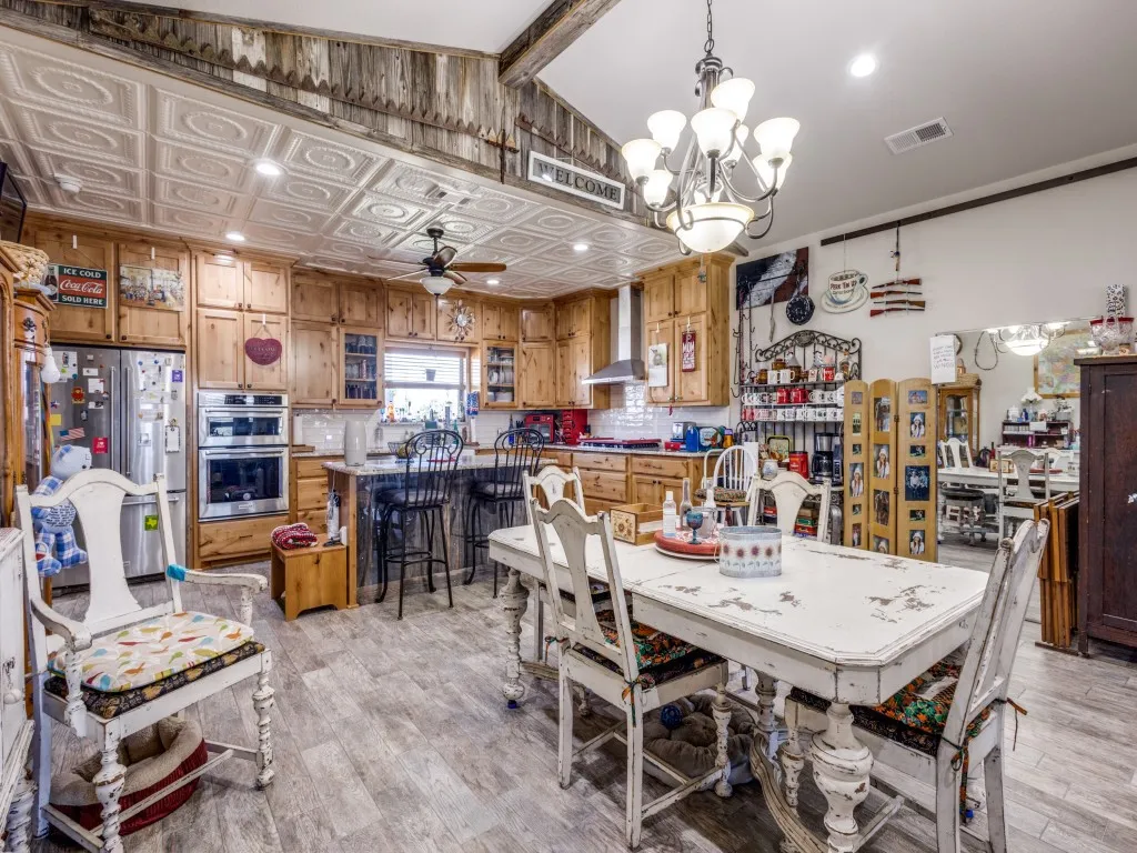 Dining area featuring ceiling fan with notable chandelier, light hardwood / wood-style flooring, and lofted ceiling