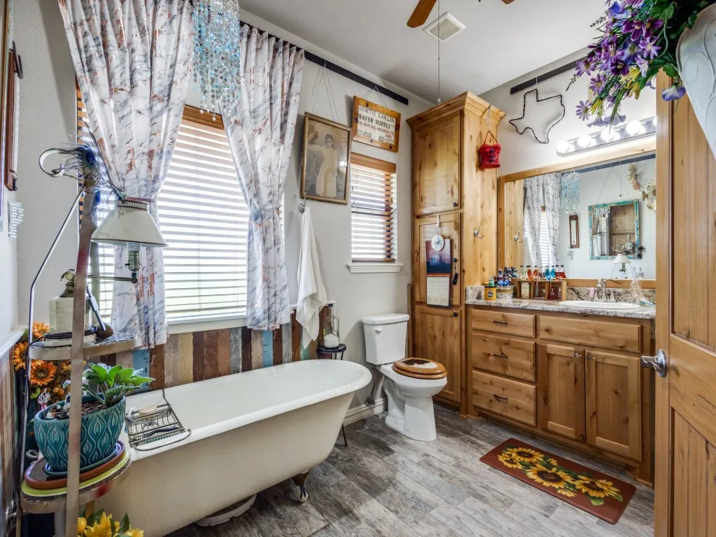 Bathroom with ceiling fan, toilet, a bath to relax in, vanity, and hardwood / wood-style floors