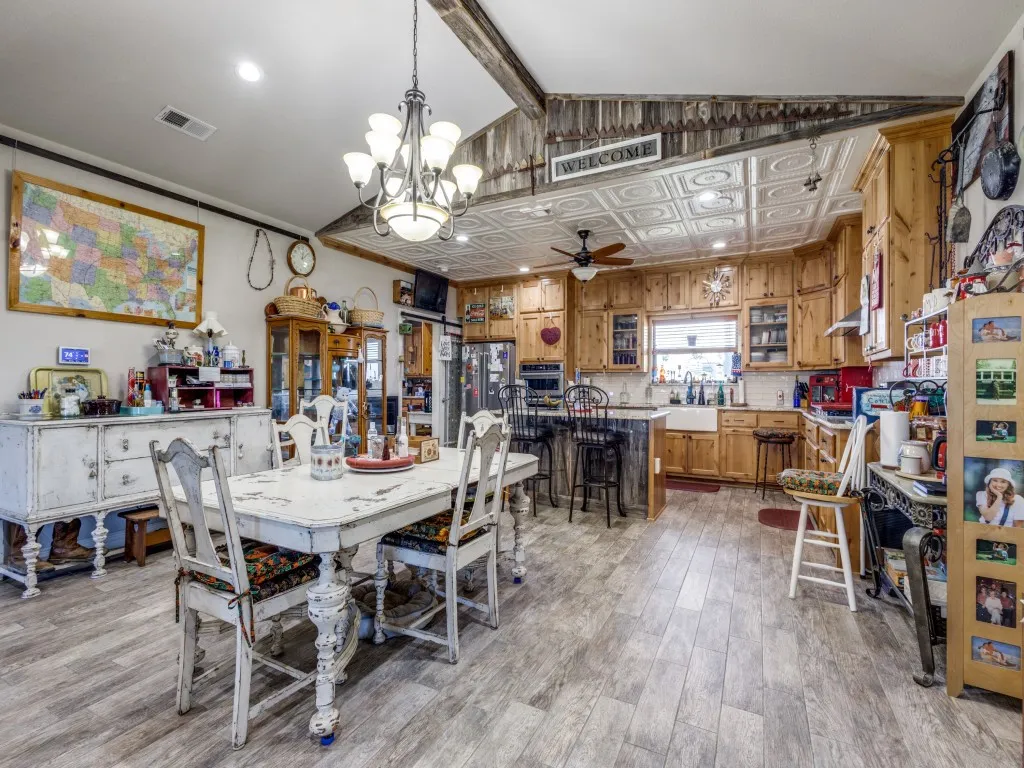 Dining area featuring vaulted ceiling, light hardwood / wood-style flooring, ceiling fan with notable chandelier, and sink