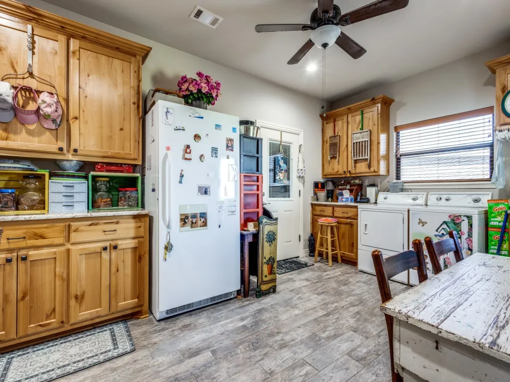 Kitchen featuring white fridge, ceiling fan, light wood-type flooring, and washing machine and clothes dryer