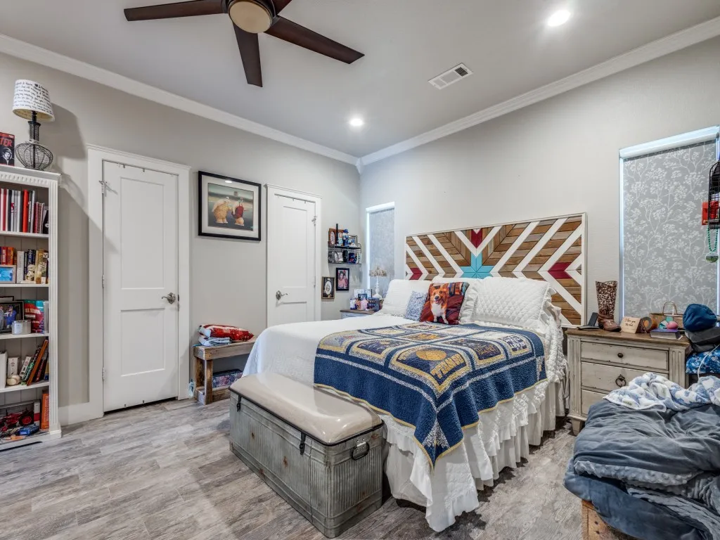 Bedroom with ceiling fan, light hardwood  floors, and crown molding