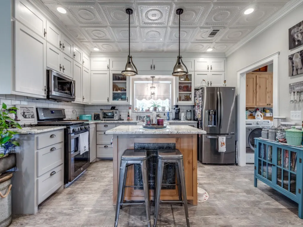 Kitchen featuring pendant lighting, white cabinets, appliances with stainless steel finishes, and a kitchen island