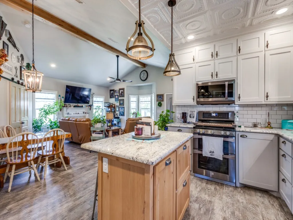 Light and bright kitchen with white cabinets, appliances with stainless steel finishes, pendant lighting, and plenty of natural light