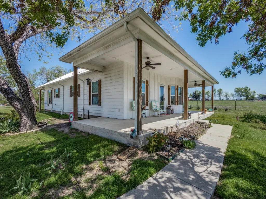 View of front of house featuring covered porch, ceiling fan, and a front yard